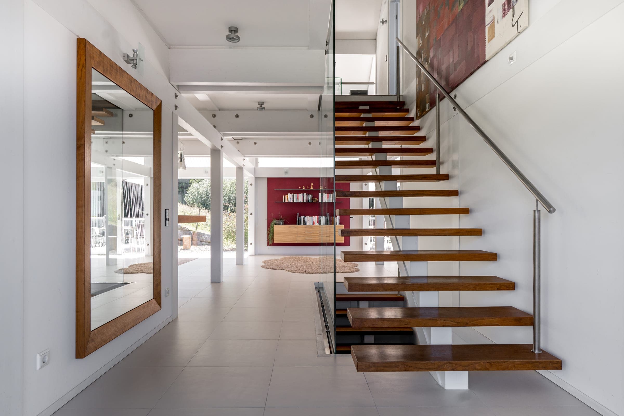 Hall with a floating wooden staircase and a view through to the terrace