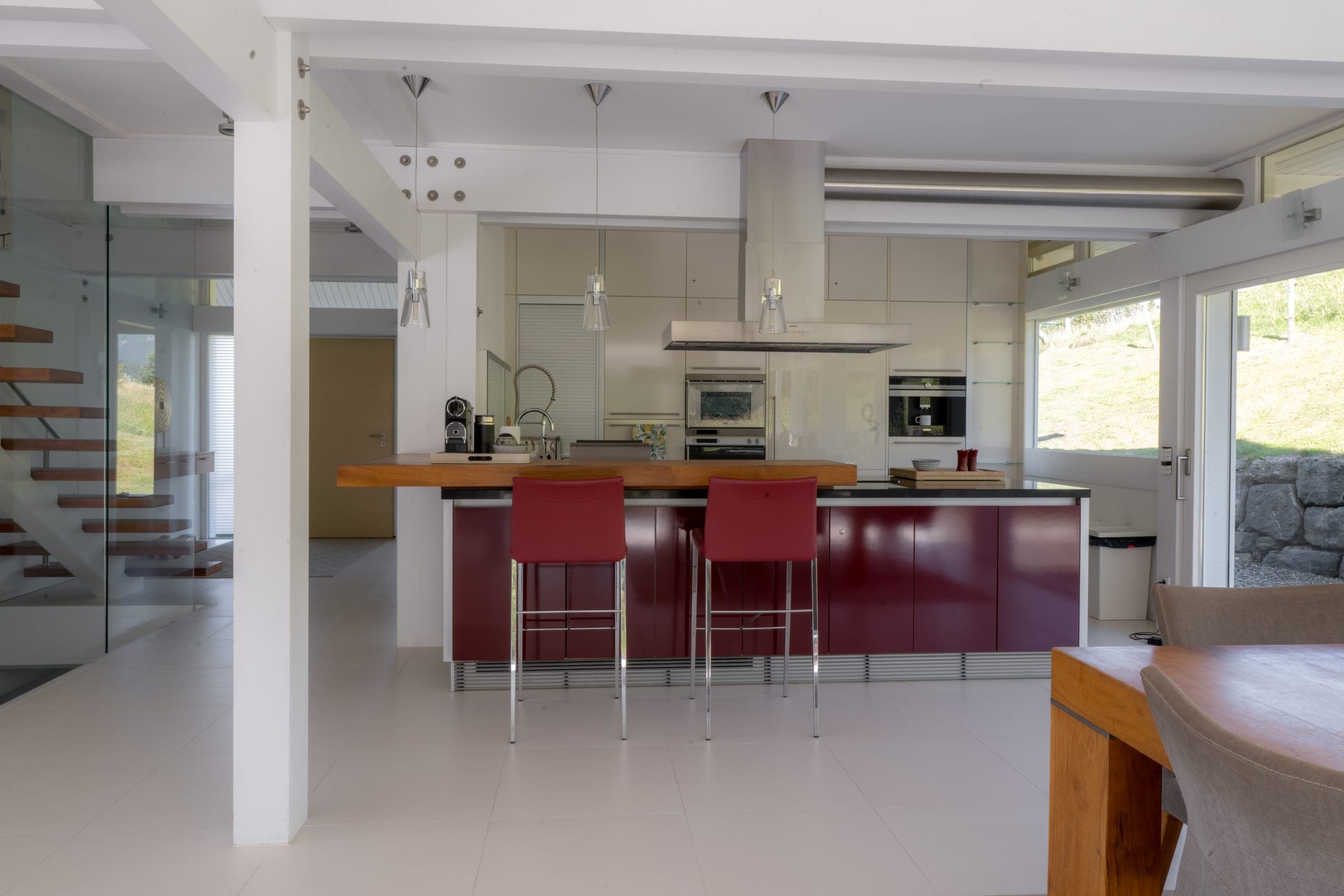 Kitchen with a deep-red island and bar stools