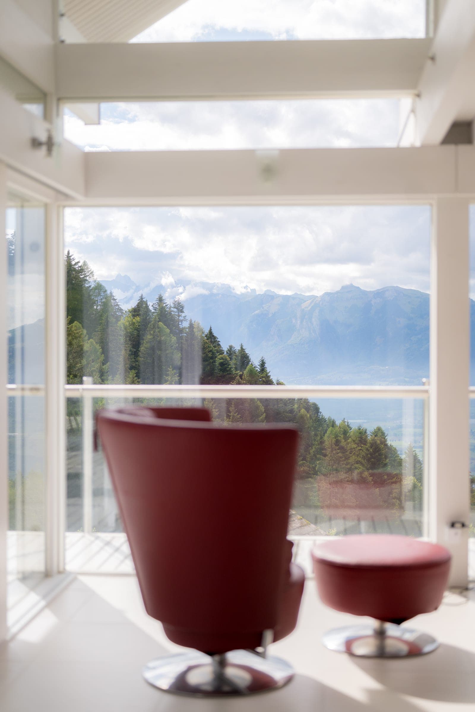 Armchair in front of the glass front with a mountain view