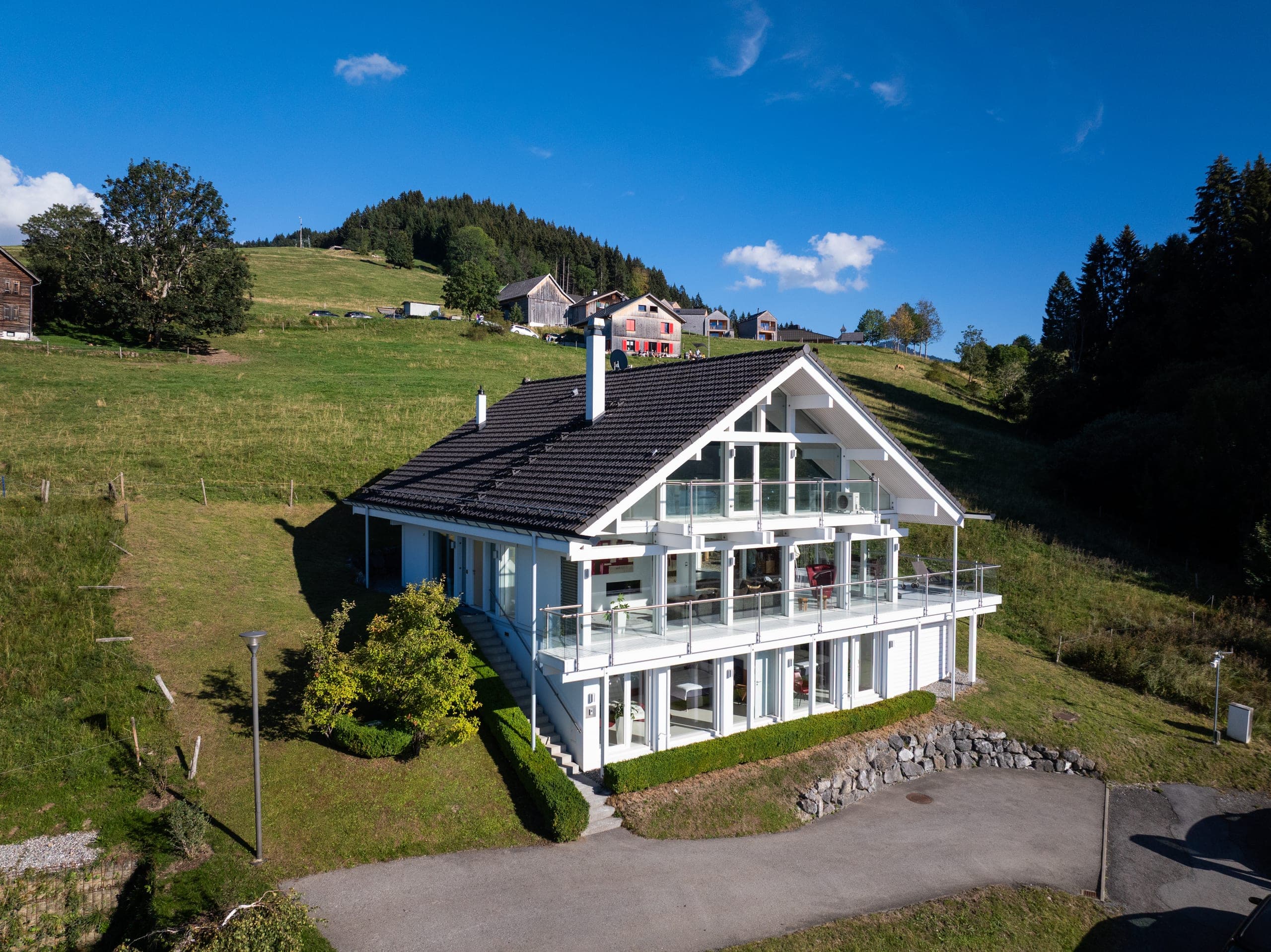 The house with its glass gable and a balcony along the whole front, meadows all around